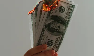 Billetes ardiendo representando el presupuesto publicitario malgastado por errores de tracking en Google Ads