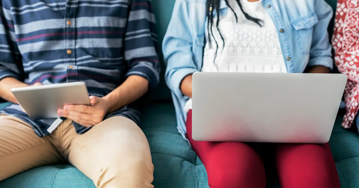 Dos personas consultando información digital en un portátil y una tableta